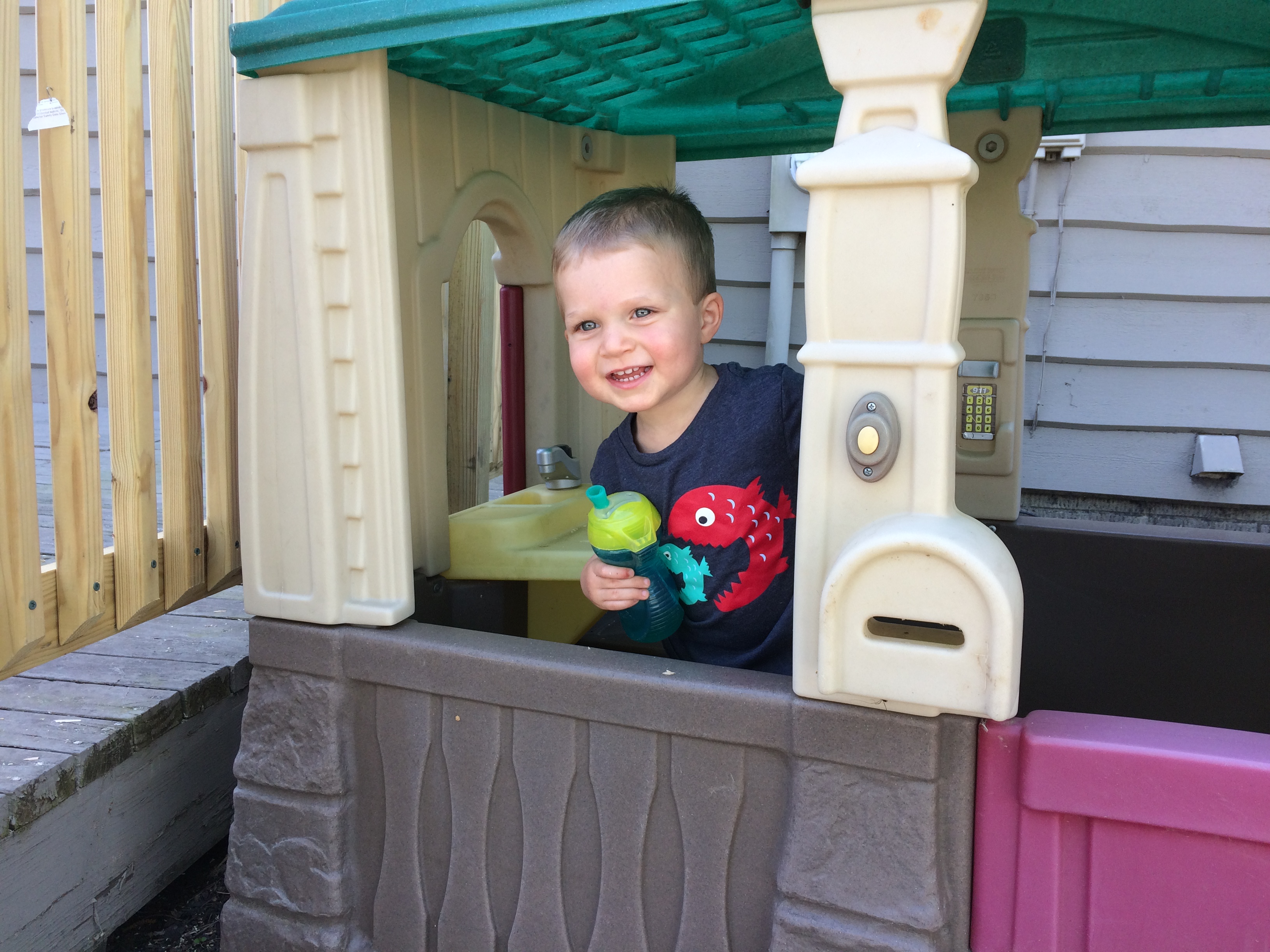 A young boy playing outside in a play house