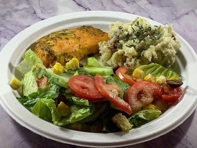 Cooked Salmon on a white plate wiht cauliflower mashed potatoes and green salad.